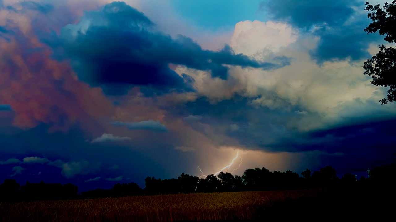 Dunkle Wolken und ein Blitz über einem Feld.