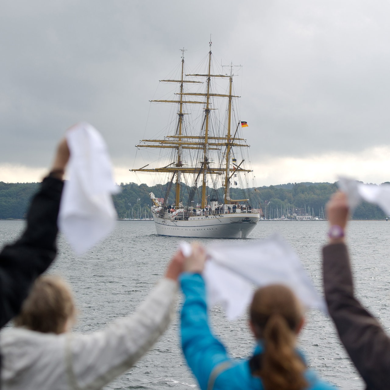 Familienmitglieder winken mit weißen Taschentüchern eine Schiff hinterher