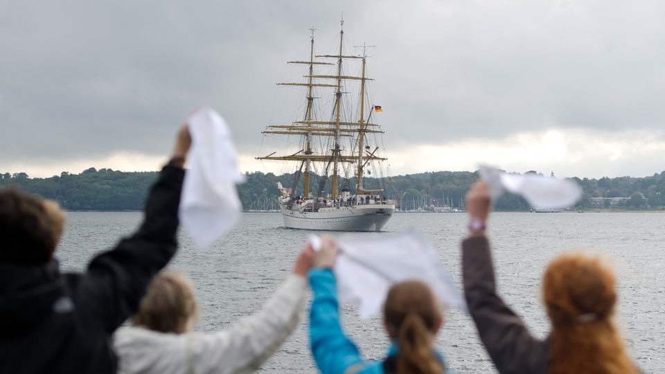 Familienmitglieder winken mit weißen Taschentüchern eine Schiff hinterher