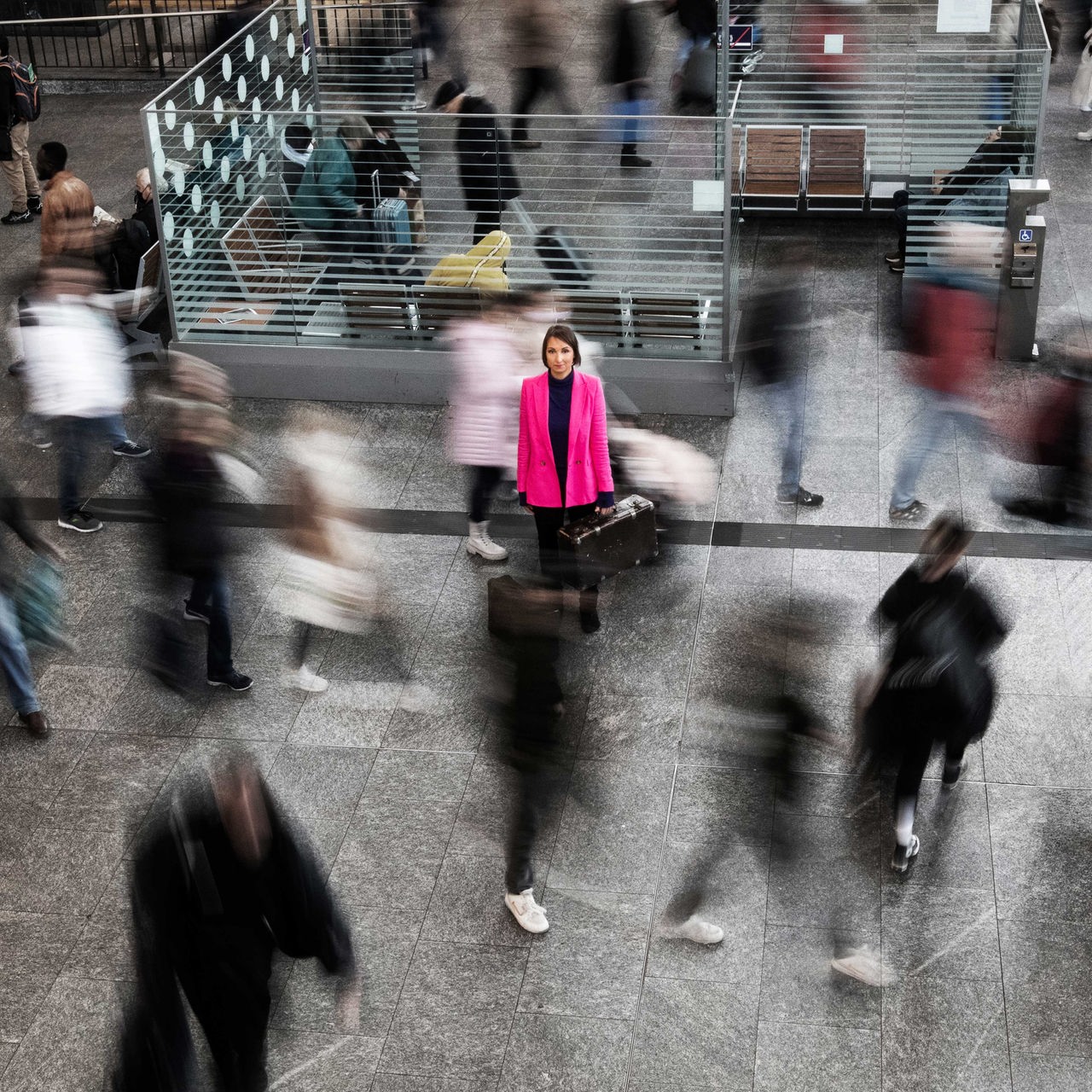 Eine Frau mit Koffer im Bahnhof inmitten von Menschen