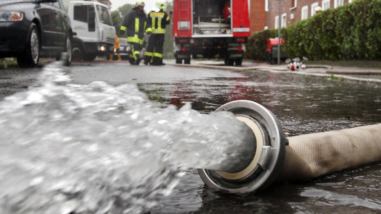 Die Feuerwehr pumpt einen Keller aus. Aus einem Schlauch sprudelt Wasser.