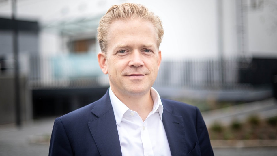 Ein blonder Mann steht vor der Halle 1 im Tabakquartier mit dem Proben- und Veranstaltungssaal der Bremer Philharmoniker. 