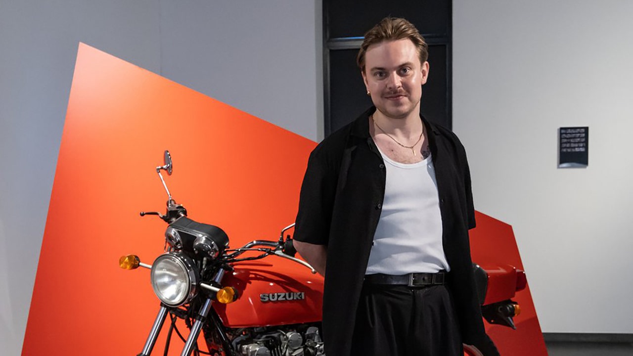 Hauptpreisgewinner Jonas Höschl steht vor einem ausgestellten Motorrad