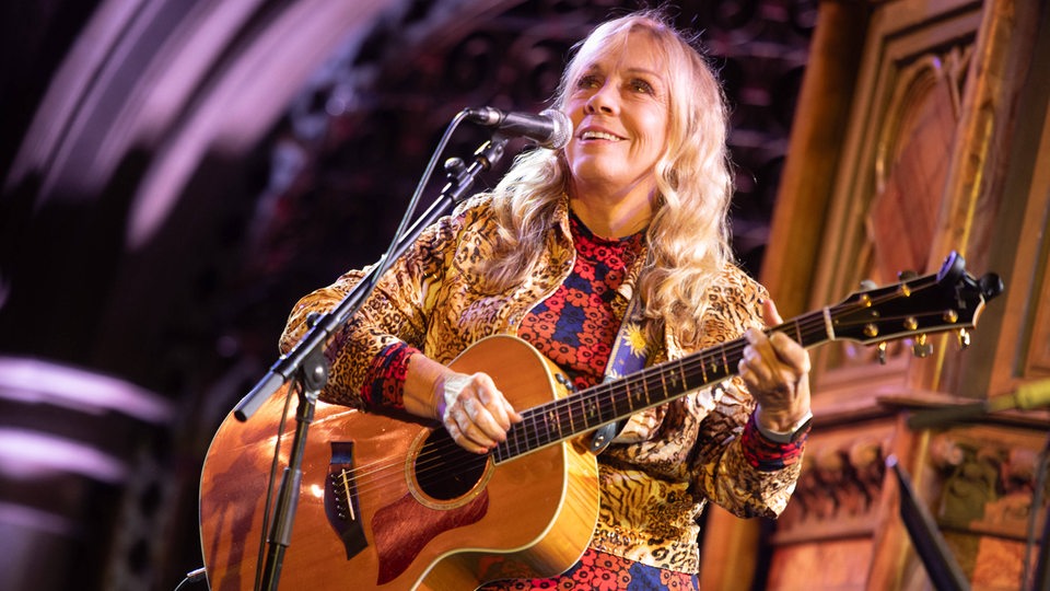 Rickie Lee Jones auf der Bühne mit klassischer Gitarre.